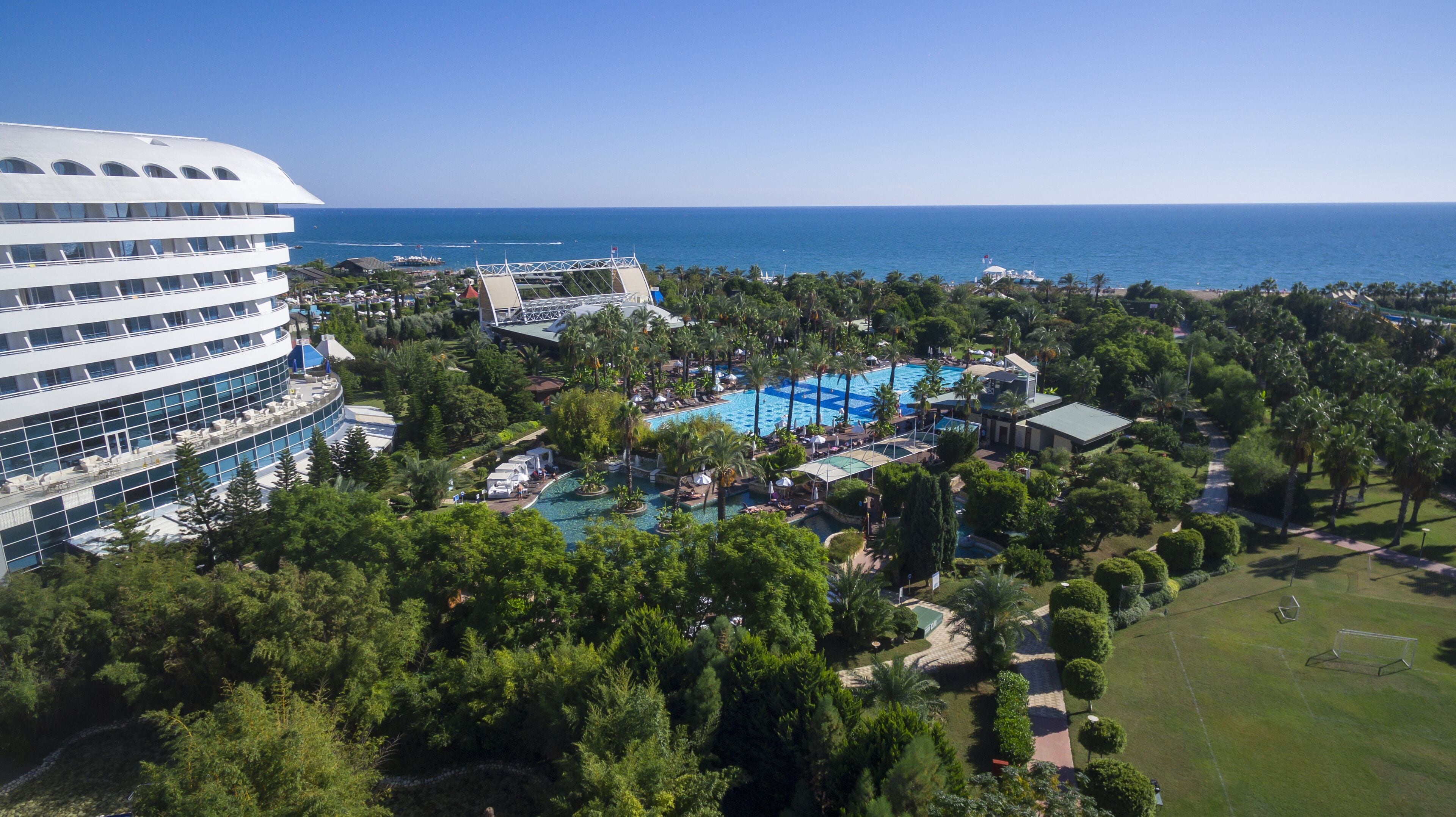 A resort with multiple swimming pools, lush greenery, and a large building with a curved facade.