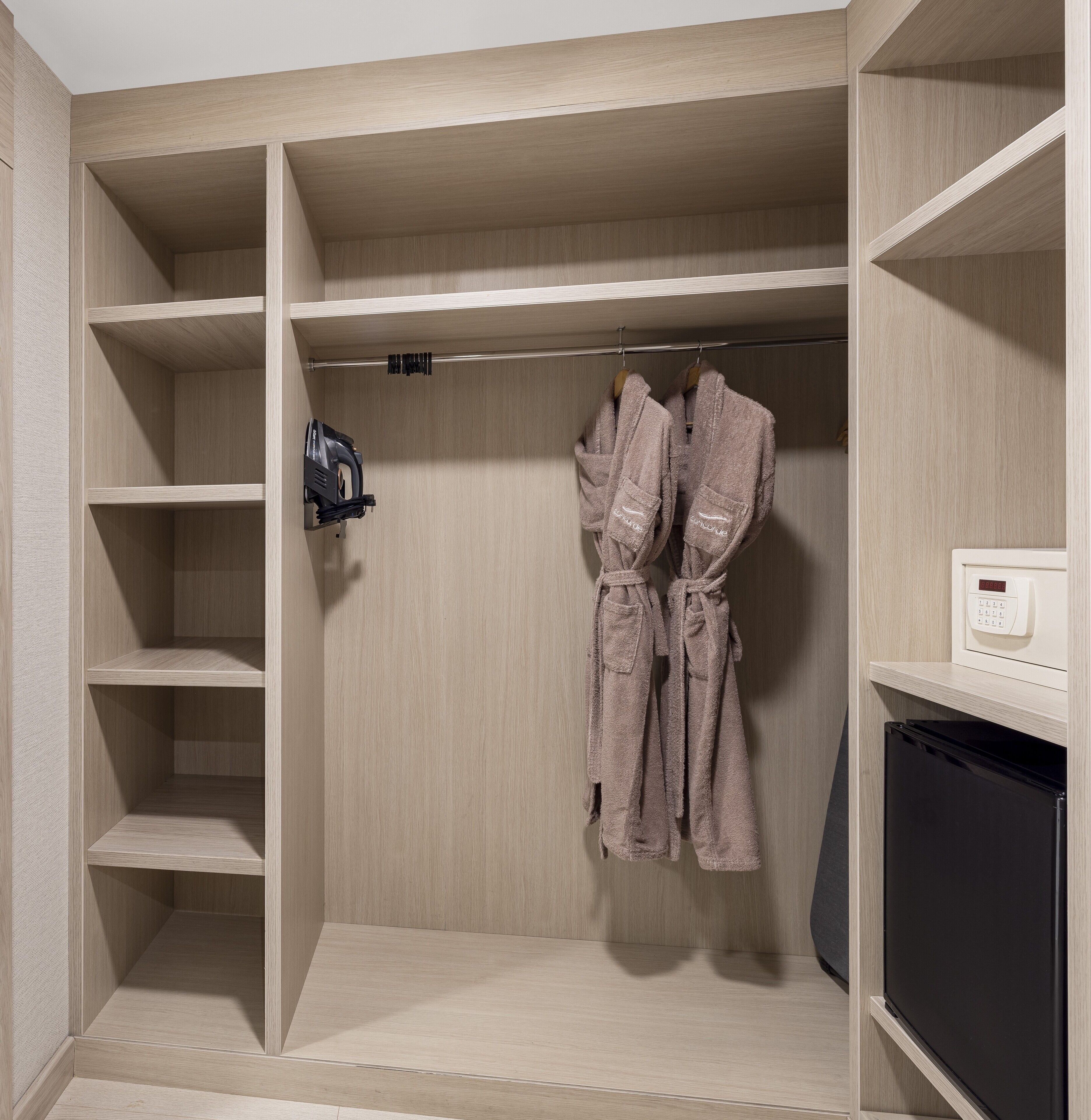A walk-in closet with multiple shelves, a hanging rod for robes, and a built-in appliance.