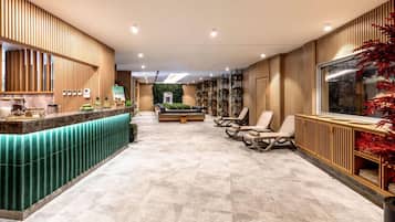 Un área de recepción con un mostrador verde, zona de asientos con sillas y una pared con listones de madera verticales.