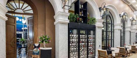 A lobby with marble flooring, wooden columns, and a wine display.