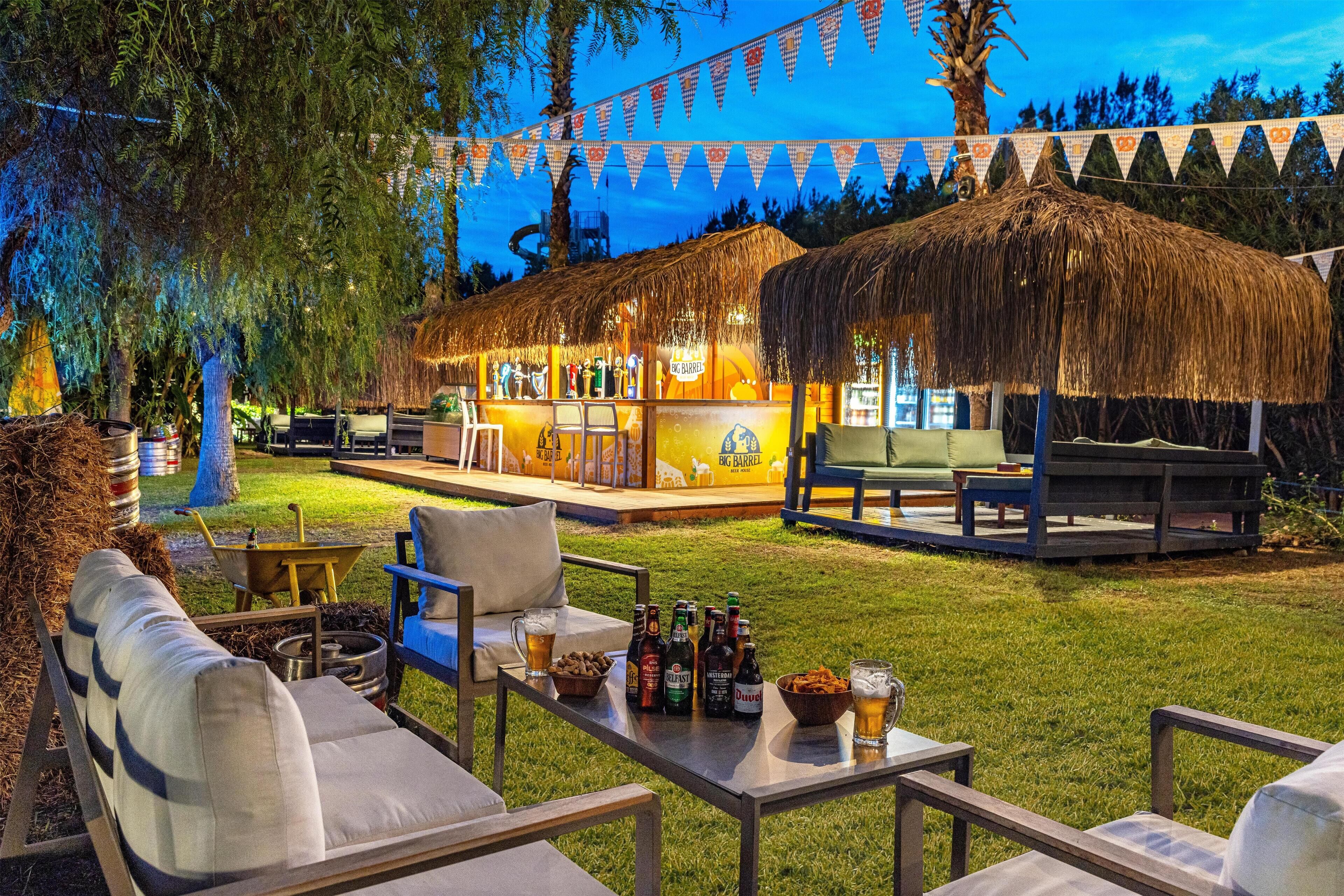 Un área de bar al aire libre con asientos y una estructura de techo de paja.