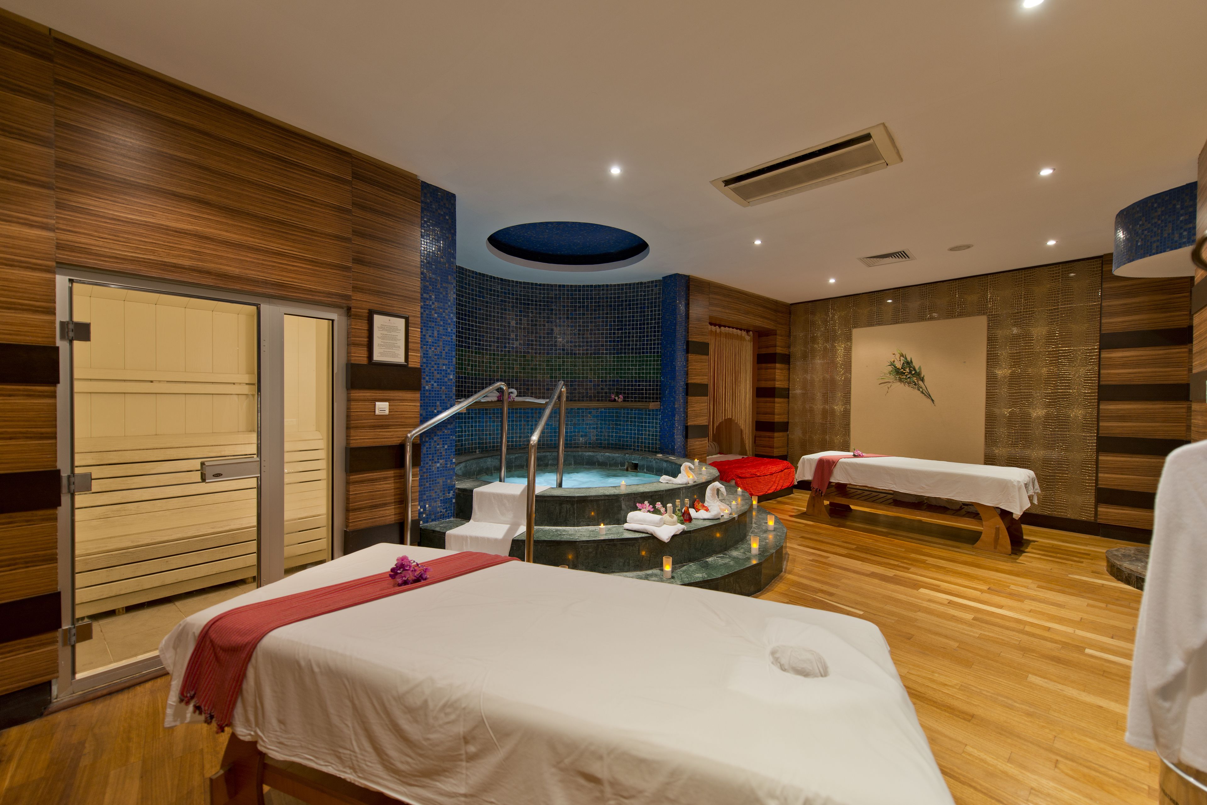 Une salle de spa équipée d’une table de massage, d’un bain à remous et d’un mur en bois.