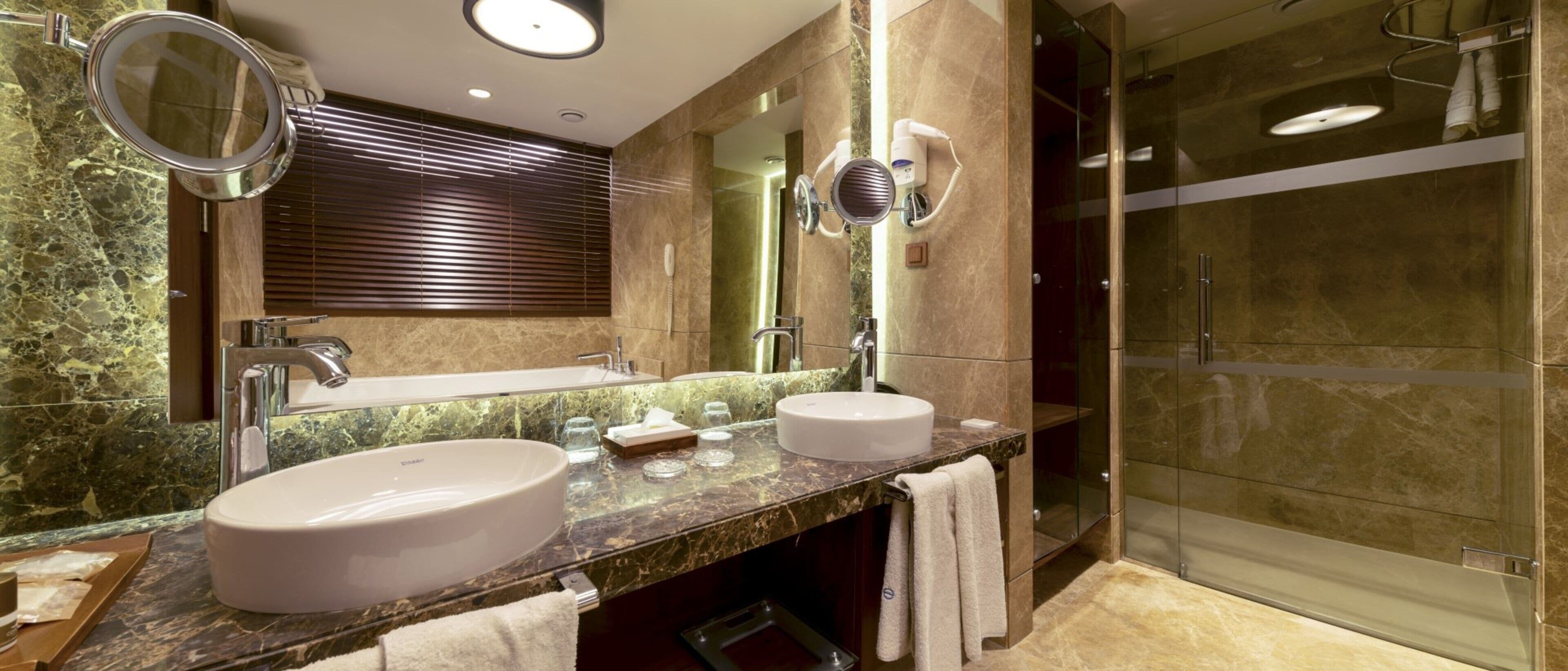 Un baño con dos lavamanos, un espejo y una cabina de ducha de vidrio.