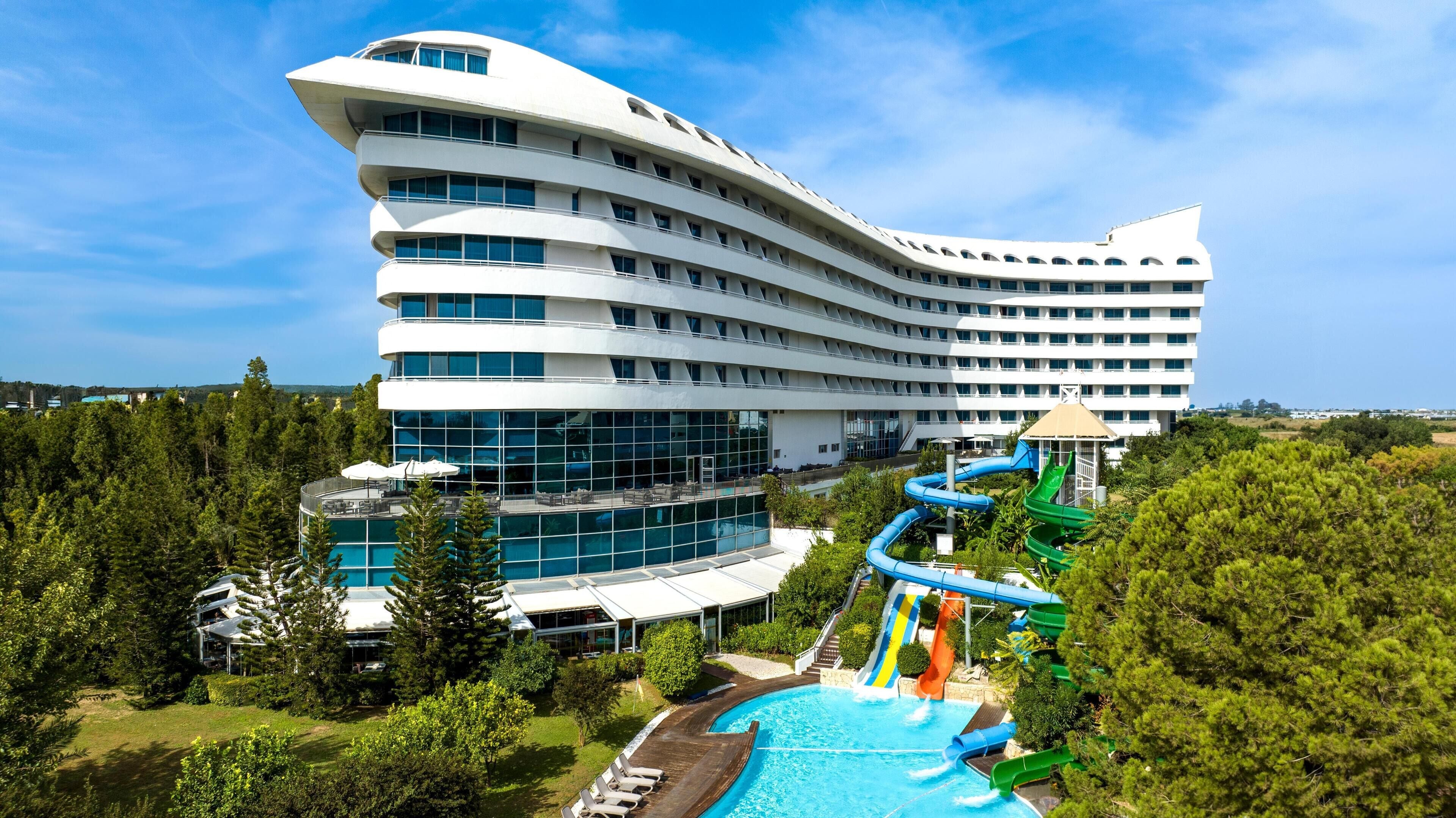 A modern hotel with a unique curved architecture, a swimming pool, and a water slide.