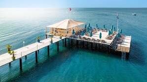 A floating structure with a covered seating area, lounge chairs, and umbrellas, connected to a dock by a walkway. - Concorde De Luxe Resort Lara Antalya - Prive Ultra All Inclusive (Antalya)
