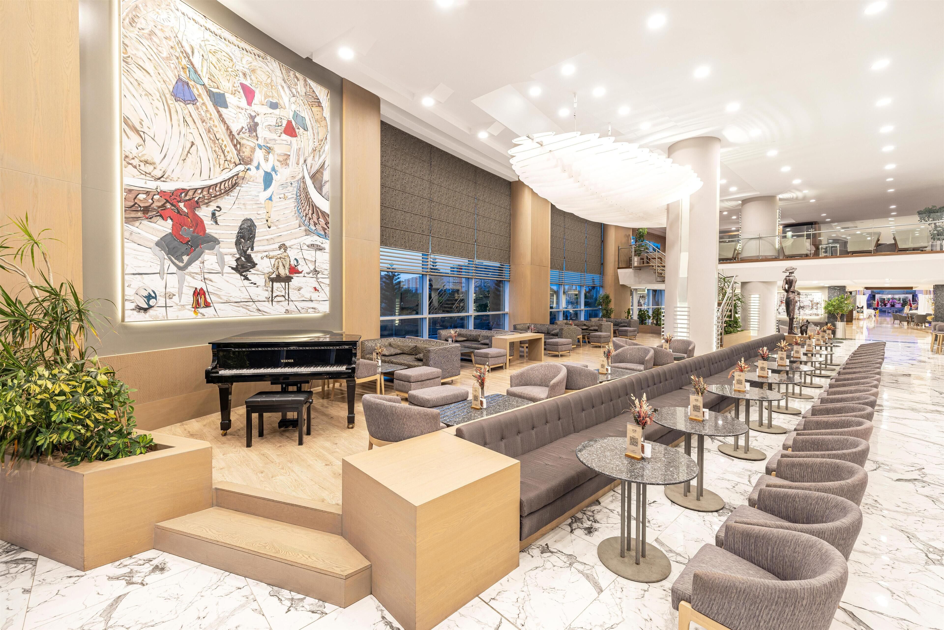 A spacious lobby with a grand piano, comfortable seating areas, and a large mural on the wall.