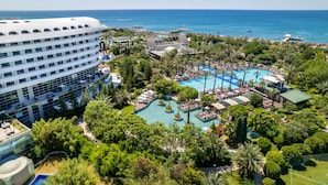 A resort with a large pool, palm trees, and a view of the ocean. - Concorde De Luxe Resort Lara Antalya - Prive Ultra All Inclusive (Antalya)