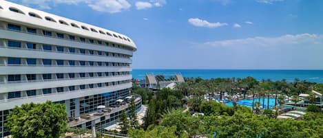 Un hotel moderno con piscina en la azotea, abundante vegetación y vista al océano.