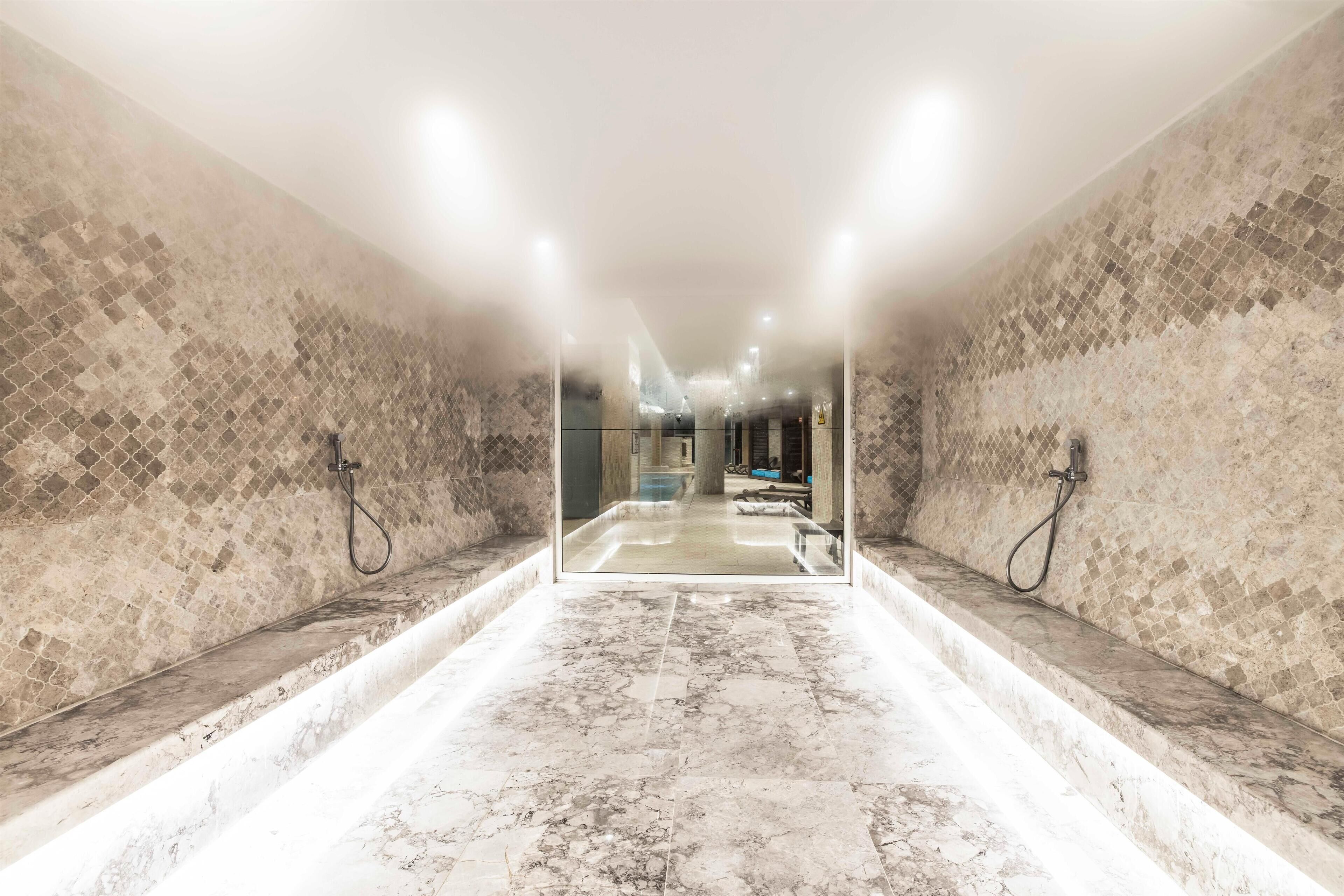 Une salle de bain moderne avec un grand miroir, deux lavabos et un sol en marbre.