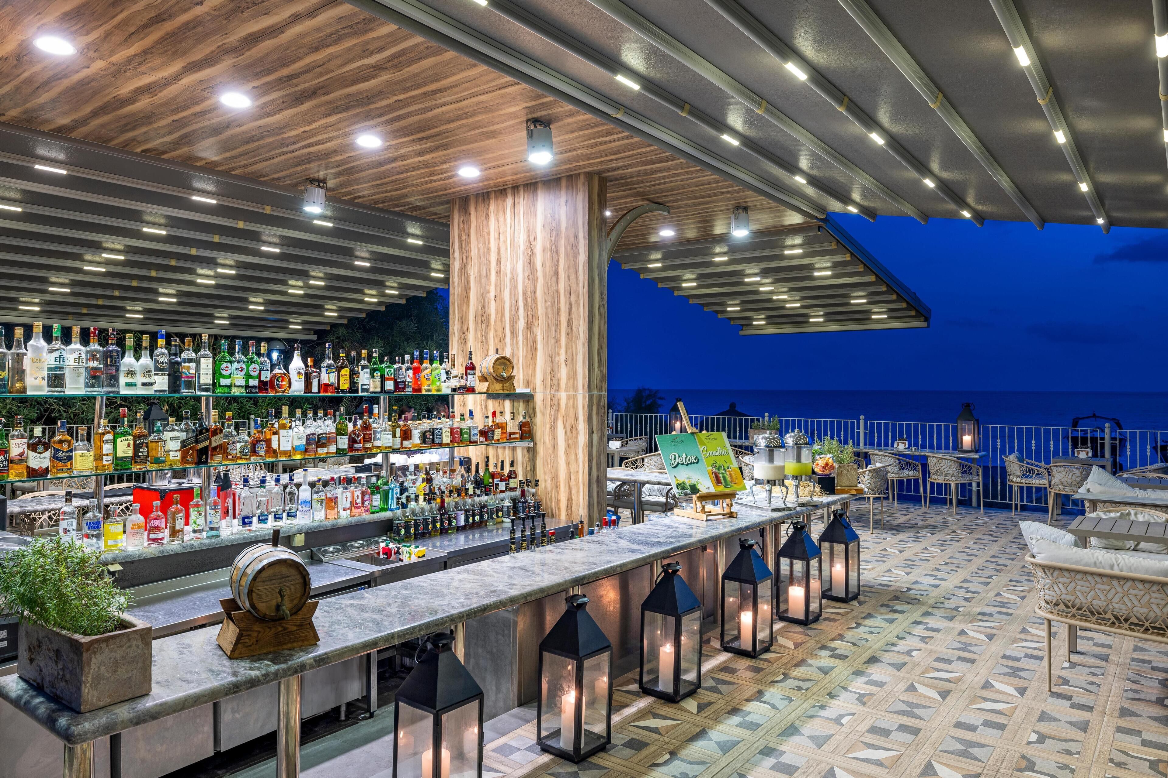 Zona de bar con una barra larga, estantes llenos de botellas y vistas al cielo nocturno.