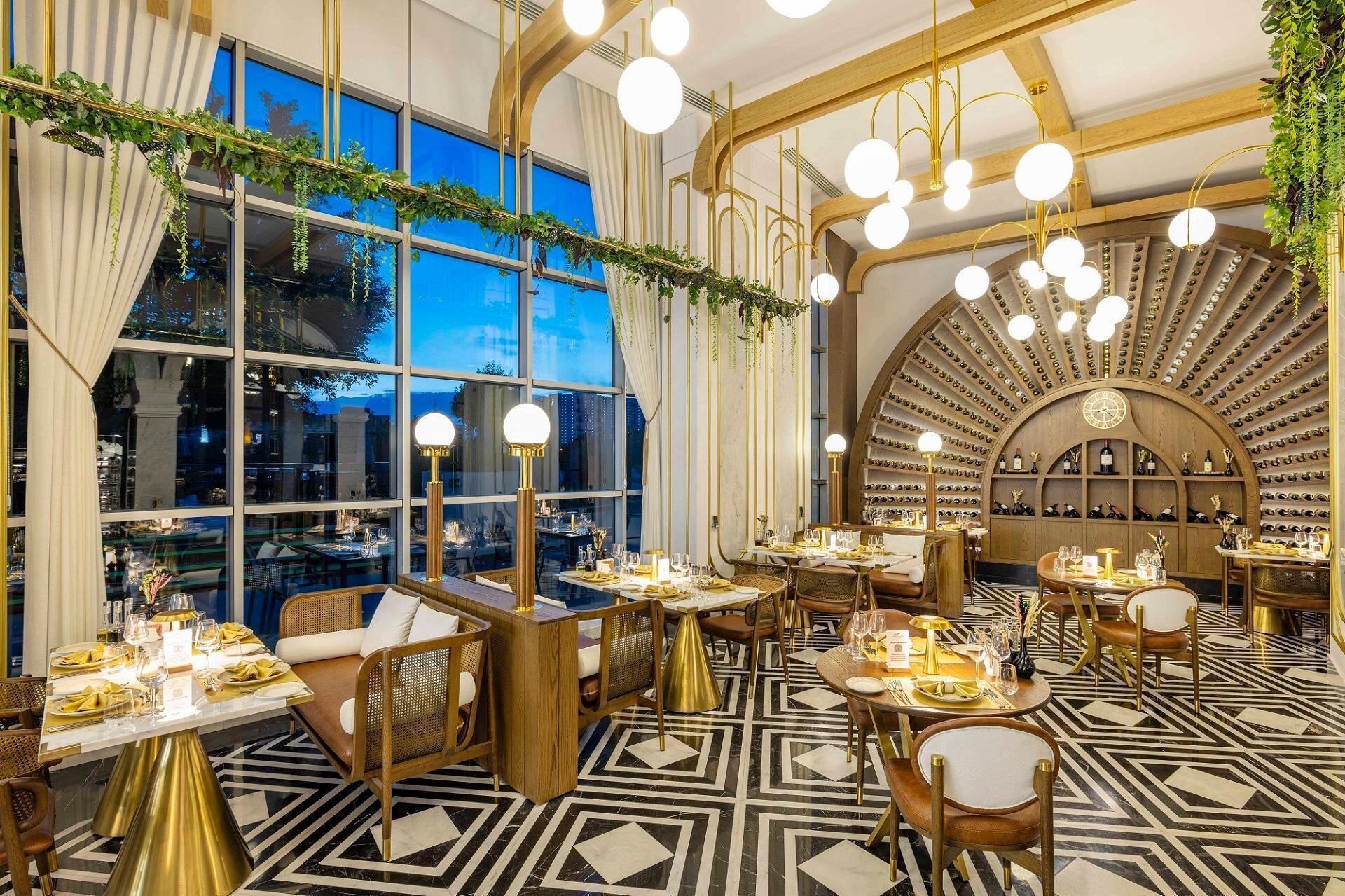 A restaurant with round tables, gold accents, and a wine cellar.