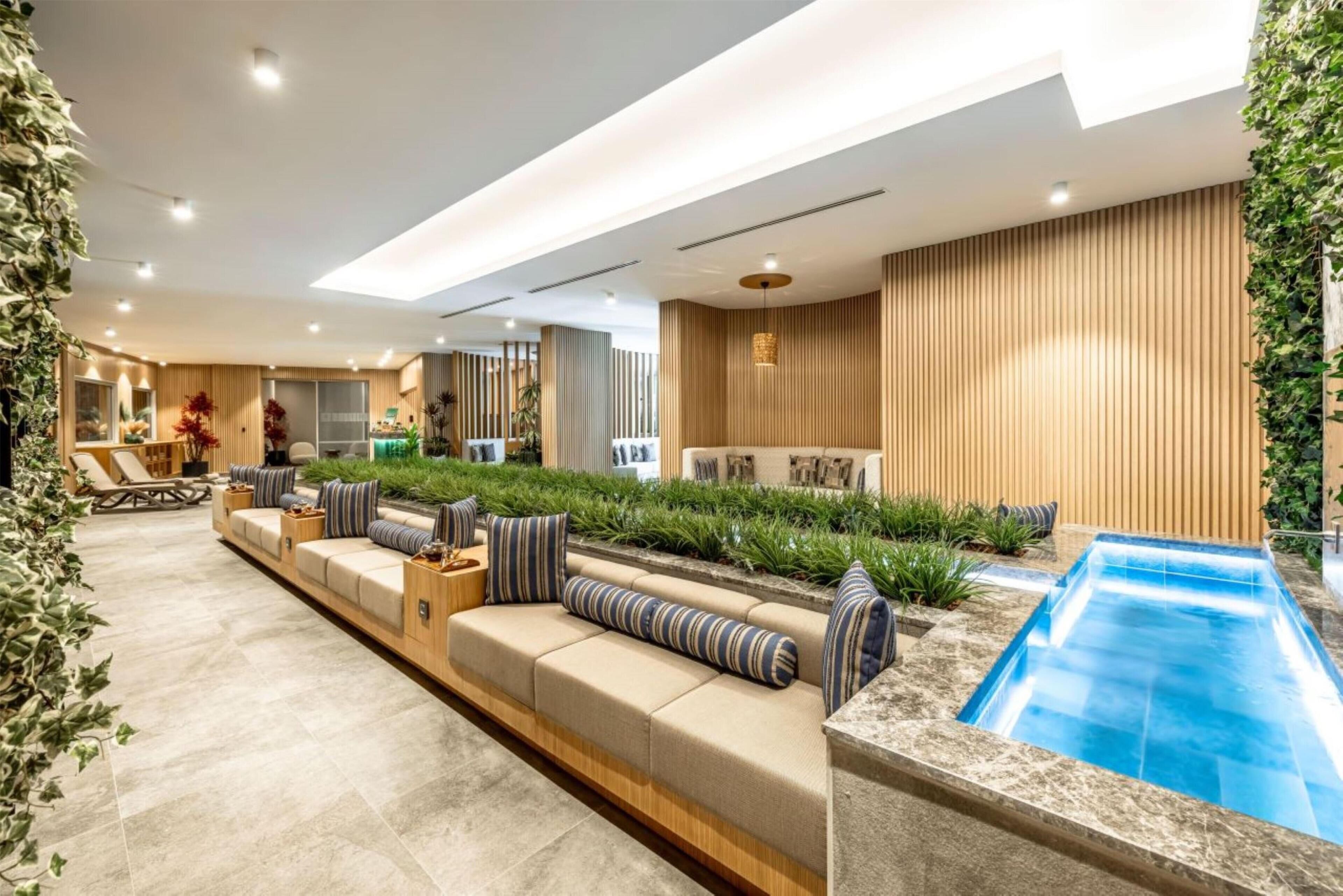 A modern indoor pool area with a long, low seating area and a small pool.