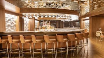 A bar area with wooden paneling, a bar counter, and multiple stools.