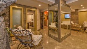 A modern interior with wicker furniture, a stone accent wall, and a television in the background. - Glorious Hotel (Istanbul)