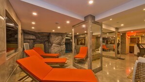 A spa area with sun loungers, a stone wall, and a mirror reflecting the room. - Glorious Hotel (Istanbul)