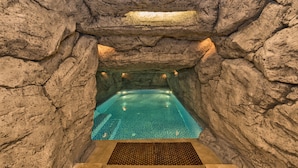 An indoor swimming pool with a rocky cave-like ceiling and walls, featuring a clear blue water surface. - Glorious Hotel (Istanbul)