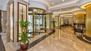 A spacious lobby with marble flooring, a glass elevator, and a reception area with a golden reception desk. - Glorious Hotel (Istanbul)