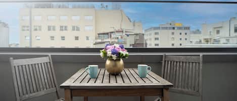 Un balcon avec une table en bois, deux chaises et un vase rempli de fleurs.