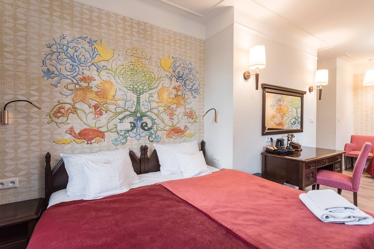 Una habitación de hotel con una cama, un escritorio, una silla y un mural en la pared.