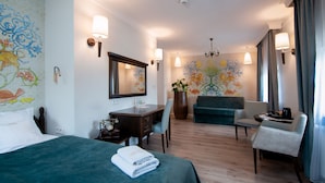 A hotel room with a bed, a desk, a chair, a sofa, and a large mirror.