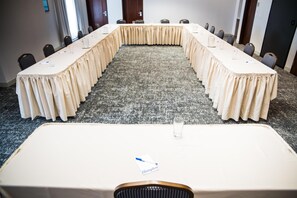 Un salón de conferencias con una larga mesa, sillas y piso alfombrado.
