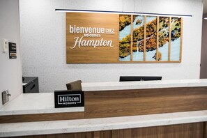 Una mesa de recepción con un cartel que dice 'Bienvenue chez Hampton' y un cartel de 'Hilton HONORS'.