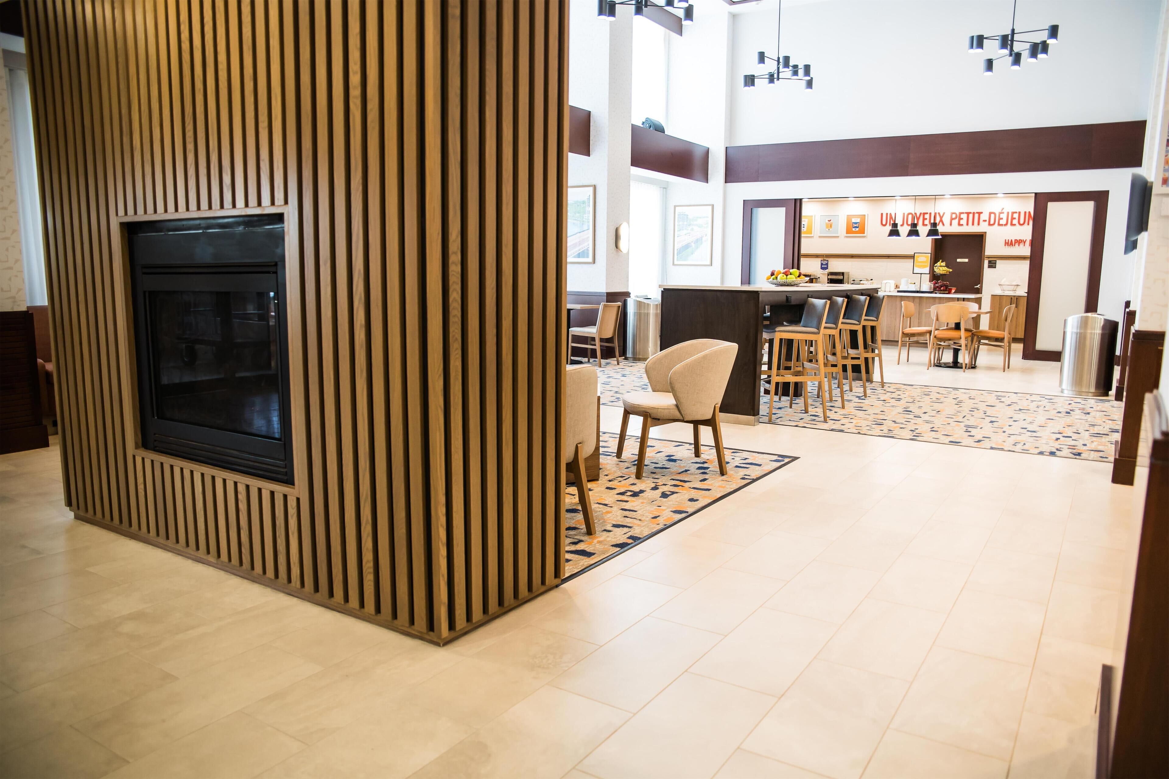 Un moderno vestíbulo de hotel con chimenea, zona de estar y comedor.