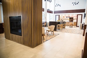 Un hall d’hôtel moderne doté d’une cheminée, d’un coin salon et d’un espace repas.