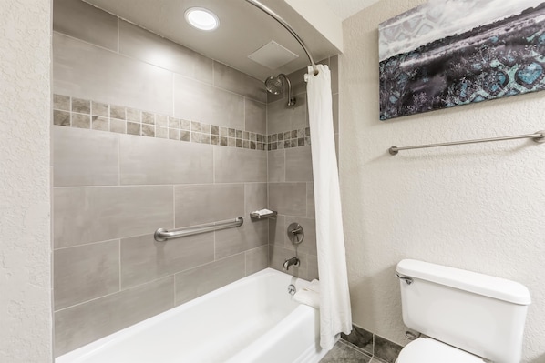 Baño con ducha, inodoro y toallero.