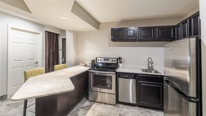 A modern kitchen with a central island, stainless steel appliances, and dark cabinetry. - Best Western Plus Sebastian Hotel & Suites (Sebastian)