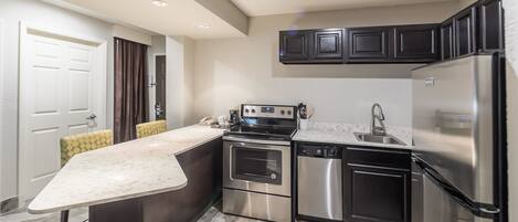 A modern kitchen with a central island, stainless steel appliances, and dark cabinetry.