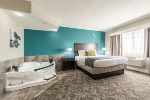 A modern hotel room with a large bed, a separate bathroom with a jacuzzi, and a view of the outdoors. - Best Western Plus Sebastian Hotel & Suites (Sebastian)