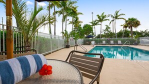 A poolside area with a pool, lounge chairs, and palm trees. - Best Western Plus Sebastian Hotel & Suites (Sebastian)