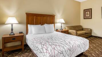 A hotel room with a large bed, two bedside tables with lamps, a brown leather armchair, and a patterned carpet.