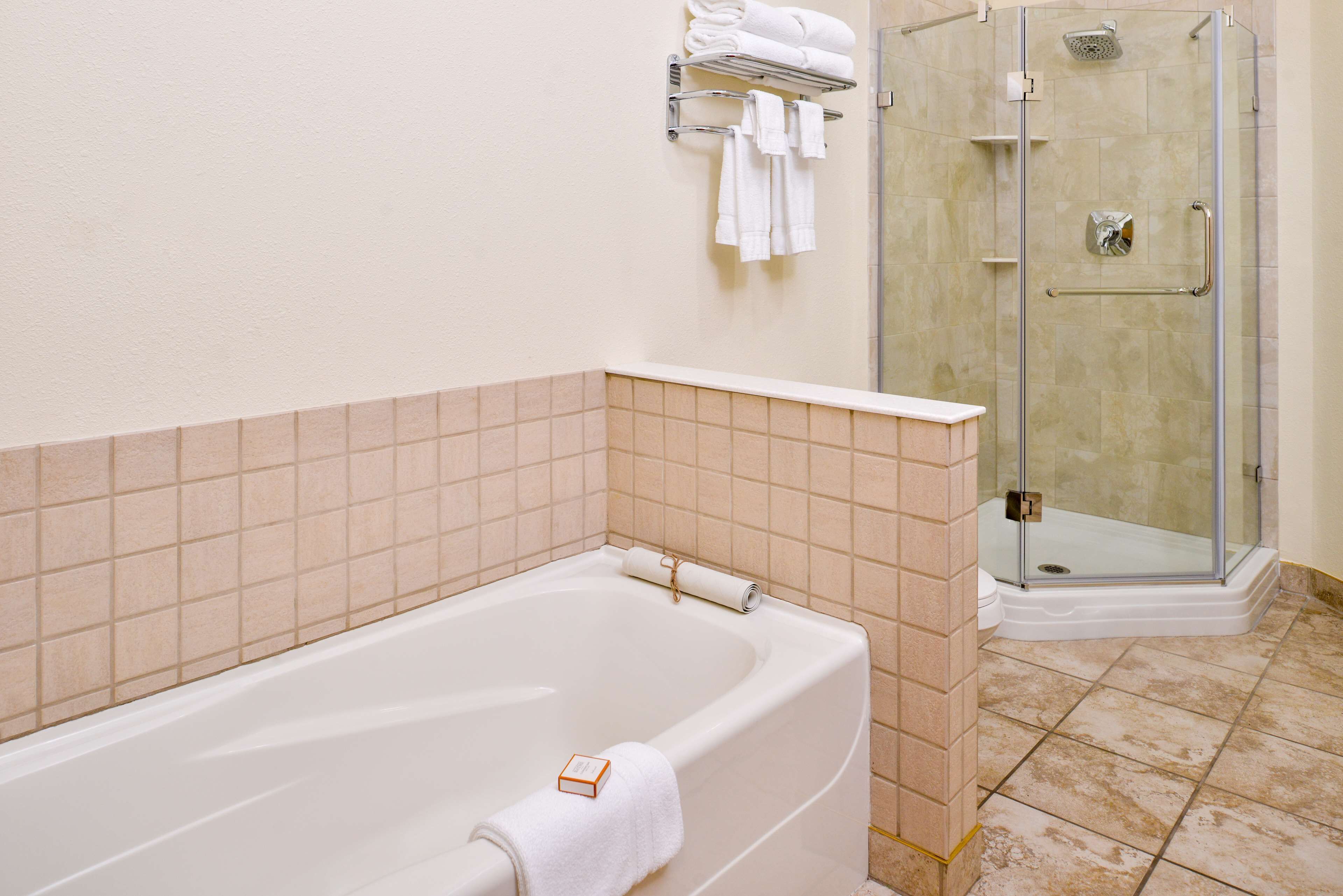 Un baño con bañera, ducha envuelta en vidrio y pared de azulejos.