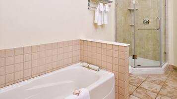 Un baño con bañera, ducha envuelta en vidrio y pared de azulejos.