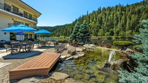 A wooden deck with outdoor furniture, a pond, and a forested hillside. - Best Western Lodge At River's Edge (Orofino)
