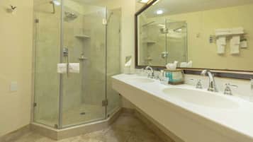 A bathroom with a glass-enclosed shower, two sinks, and a large mirror.