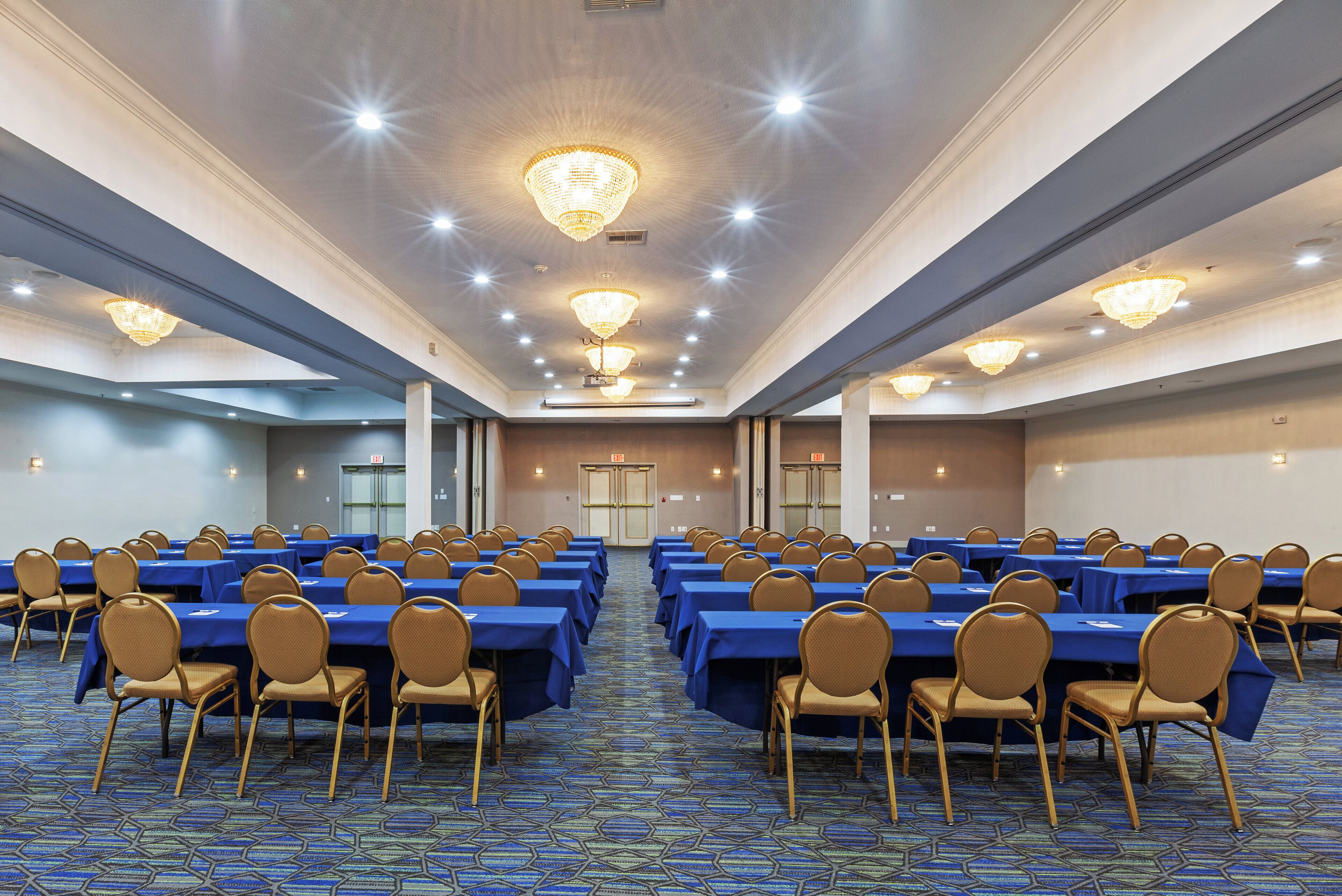 A conference room with rows of tables and chairs, a patterned carpet, and a chandelier.
