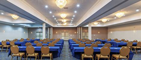 A conference room with rows of tables and chairs, a patterned carpet, and a chandelier.