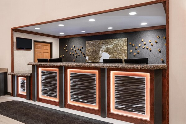 Una recepción con estructura de madera, iluminación empotrada y un mapa en la pared.