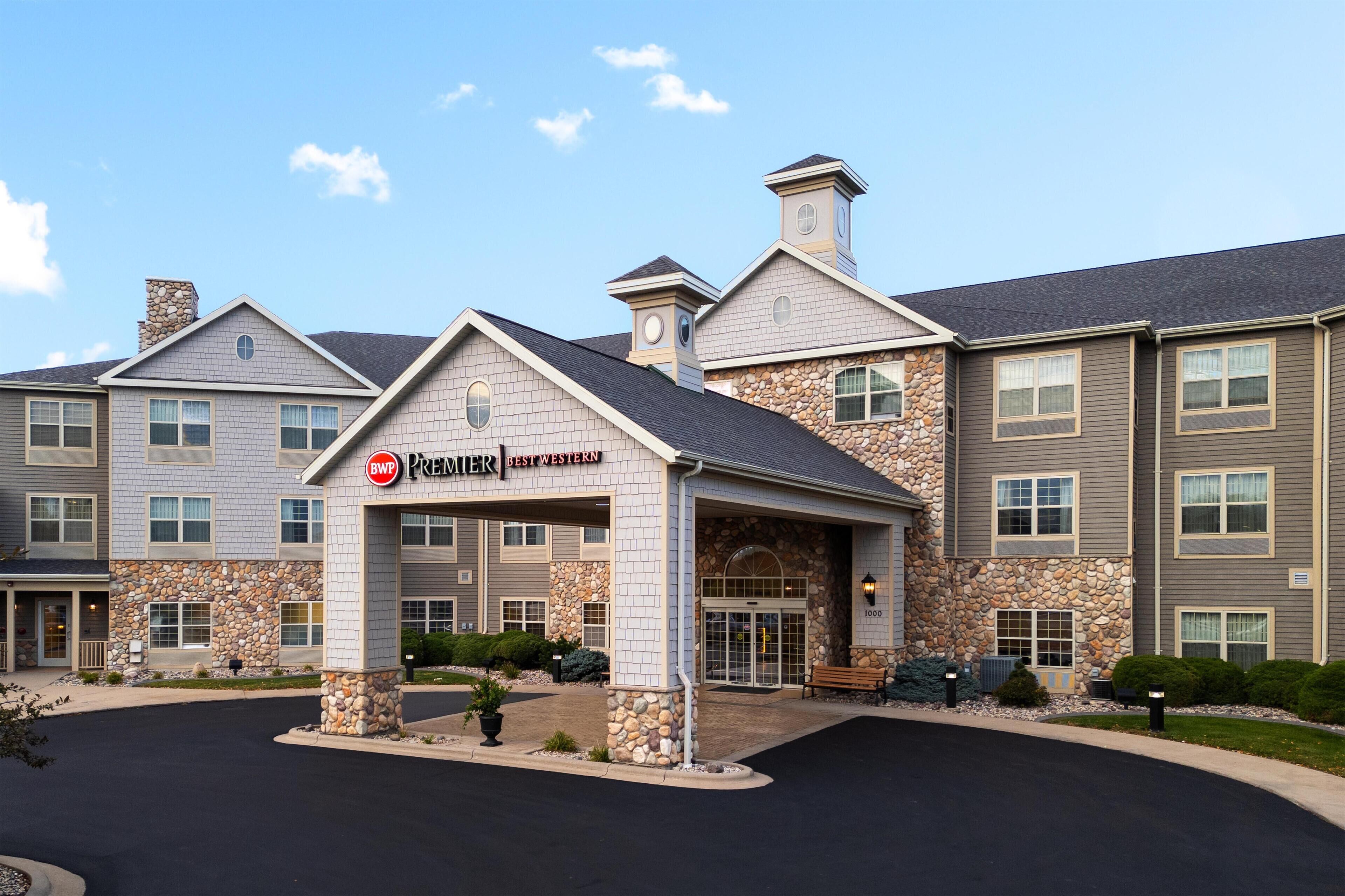 A multi-story hotel with a stone facade, a covered entrance, and a clear sky.
