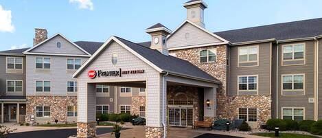 A multi-story hotel with a stone facade, a covered entrance, and a clear sky.