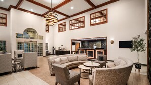 A spacious living area with a curved sectional sofa, a round coffee table, and a fireplace. There are multiple windows with wooden frames and a large arched window.