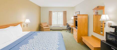 A hotel room with a bed, a desk, a chair, a television, and a mirror.
