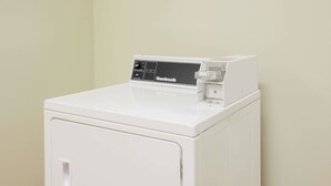 Lavadora blanca de carga frontal, compacta, con panel de control superior.