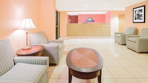Un hall de hotel con una recepción, zona de estar y una lámpara.