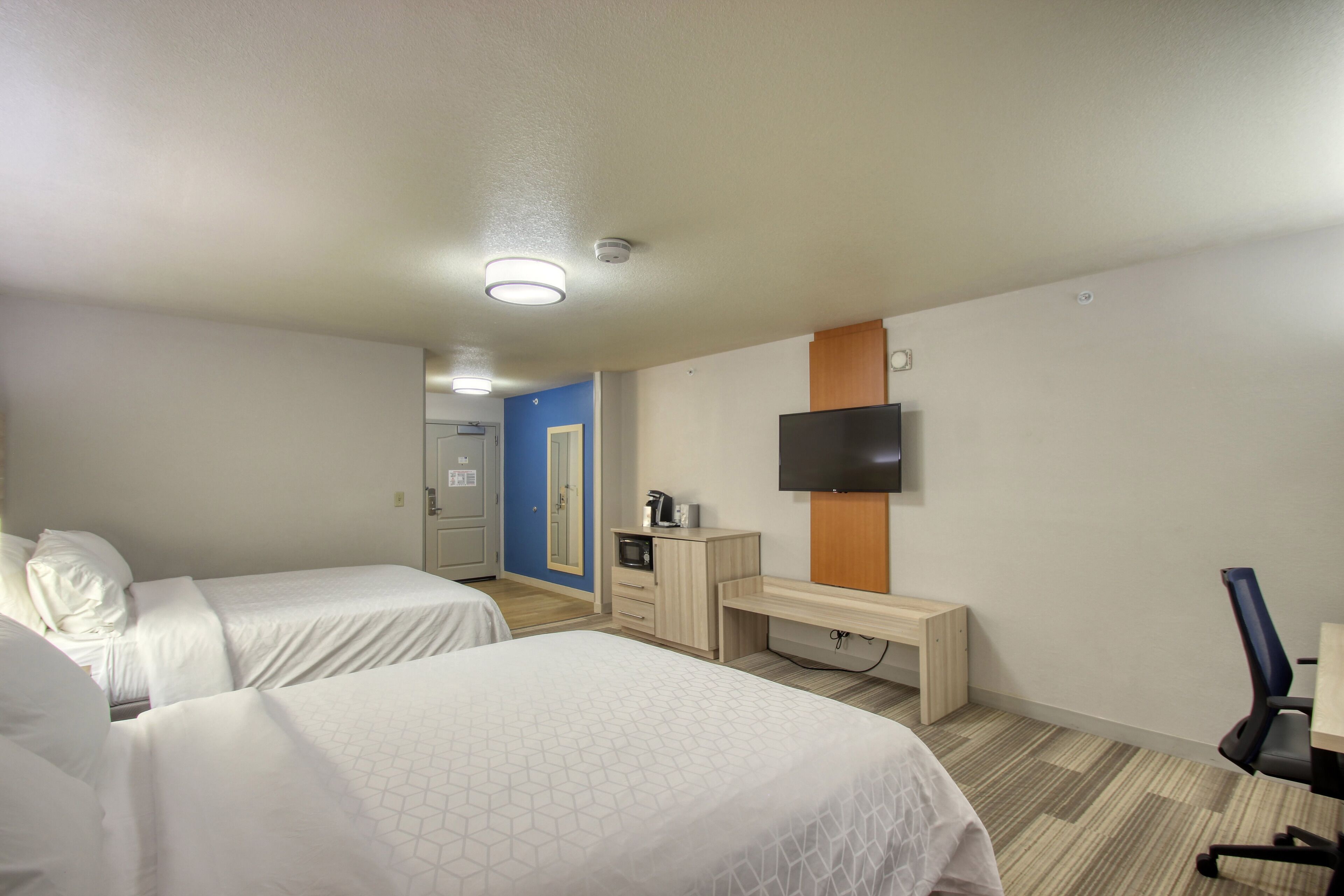 Une chambre d’hôtel avec deux lits, un bureau, une télévision et une petite kitchenette.