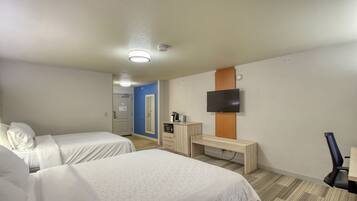 A hotel room with two beds, a desk, a TV, and a small kitchenette.