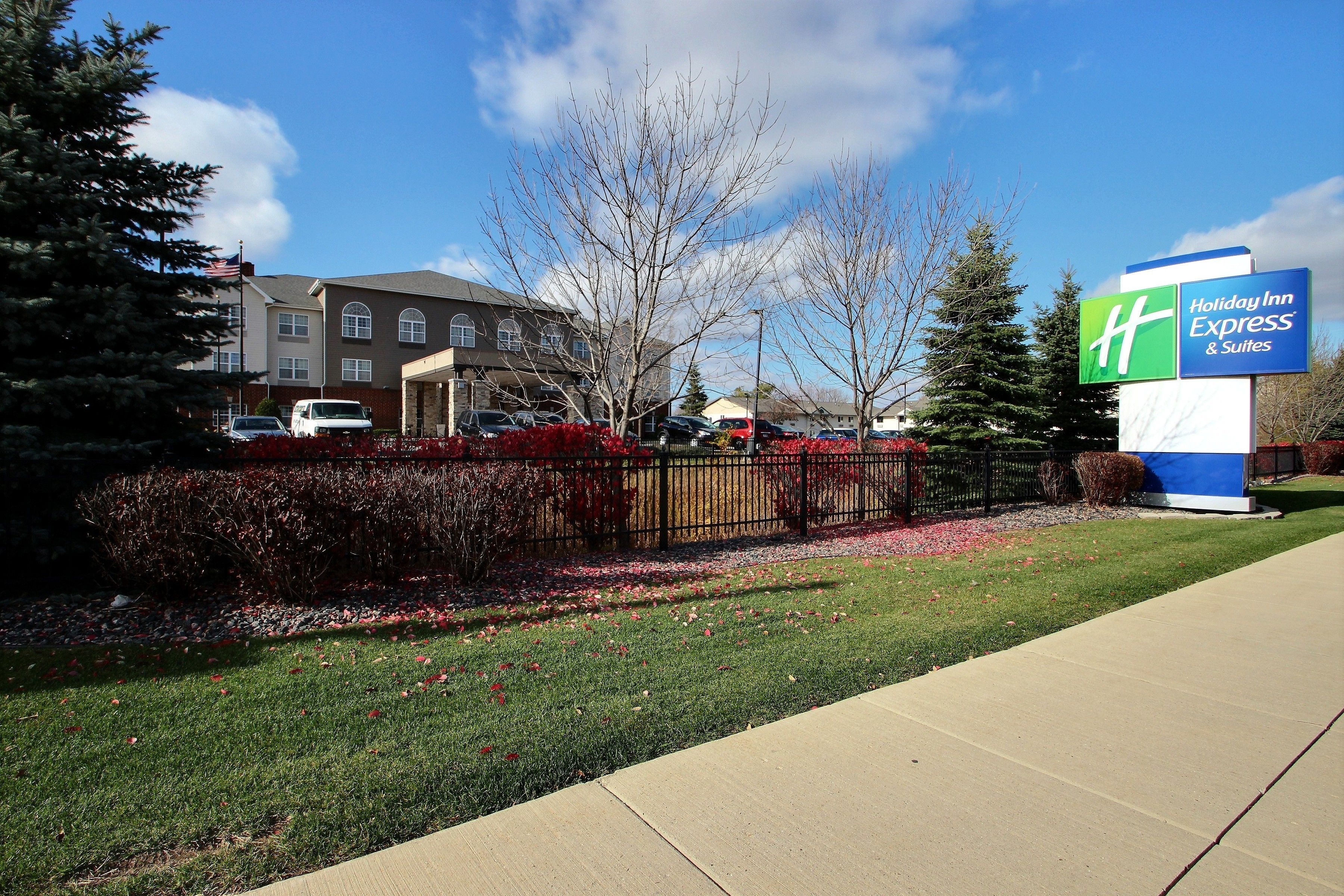 A Holiday Inn Express & Suites sign, a parking lot, and a building with a flag.